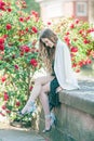 Portrait of a young beautiful slim long-haired woman in a romantic black and white dress near a red blooming rose in the center of Royalty Free Stock Photo