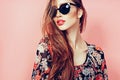 Portrait of young beautiful slim woman in sexy dress with sensual lips in studio wearing sunglasses smiling and posing Royalty Free Stock Photo