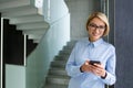 Portrait of a young beautiful smiling business woman leaning against a wall and standing in an office building, looking Royalty Free Stock Photo