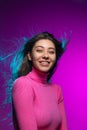 Portrait of young beautiful smiling girl with glossy long hair isolated on purple studio background in magenta neon Royalty Free Stock Photo