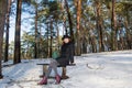 Portrait of a young beautiful smiling red hair european girl wearing black hat sitting on bench in forest Royalty Free Stock Photo