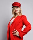 Portrait of young beautiful smiling woman in stylish elegant deep red official suit, red cap and massive earings touching peak Royalty Free Stock Photo