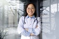 Portrait of a young beautiful and successful Asian woman inside a clinic office, a doctor smiling and looking at the Royalty Free Stock Photo