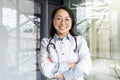 Portrait of a young beautiful and successful Asian woman inside a clinic office, a doctor smiling and looking at the Royalty Free Stock Photo