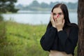 Portrait of a young beautiful surprised and shocked woman, she covers her mouth with her hands. Outdoor Royalty Free Stock Photo