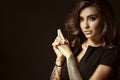 Portrait of young beautiful tattooed woman with luxuriant shining wavy hair and perfect make up holding hands in shooting gesture