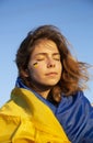 Portrait of a young beautiful tired but not broken woman wrapped in Ukraine flag Royalty Free Stock Photo