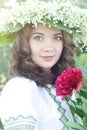 Portrait of a young beautiful in traditional Ukrainian embroidered shirt and a wreath of lilies of the valley