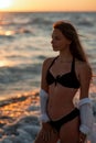 Portrait Young beautiful woman in black bikini and white shirt on a tanned body on the beach at sunset. Soft selective focus Royalty Free Stock Photo