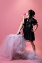 Portrait of young beautiful woman in black evening little dress isolated on pink background. Concept of holiday, fashion Royalty Free Stock Photo