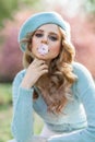 Portrait of young beautiful woman with blond hair wearing blue beret and holding flower in her mouth. Royalty Free Stock Photo