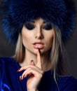 Portrait of young beautiful woman in blue purple fashion arctic fox winter fur ear flap hat Royalty Free Stock Photo