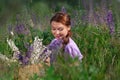 Young beautiful woman with bouquet of flowers in basket at summer nature sitting among grass. Pretty vintage girl in