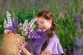 Young beautiful woman with bouquet of flowers in basket at summer nature sitting on grass. Pretty vintage girl in