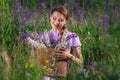 Portrait of young beautiful woman with bouquet of flowers in basket at sunny field. Pretty vintage girl