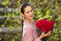 Portrait of a young beautiful woman with a bouquet of red roses in spring park Royalty Free Stock Photo