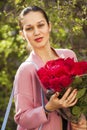 Portrait of a young beautiful woman with a bouquet of red roses in spring park Royalty Free Stock Photo