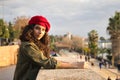 Portrait of a young and beautiful woman, brunette, with curly hair, with a green jacket and red beret, leaning on a stone wall. Royalty Free Stock Photo