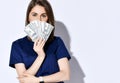 Portrait of young beautiful woman dentist, doctor, nurse holding fan of dollars cash bills in front of her face Royalty Free Stock Photo