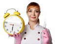 Portrait of young beautiful woman doctor or nurse in white special uniform and gloves holding syringe and alarm clock in hands Royalty Free Stock Photo