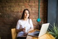 Portrait of a young beautiful woman enjoying coffee during work on portable laptop computer, charming female student using net-boo Royalty Free Stock Photo