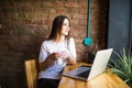 Portrait of a young beautiful woman enjoying coffee during work on portable laptop computer, charming female student using net-boo Royalty Free Stock Photo