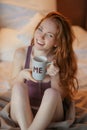 Portrait of young beautiful woman her hands holding cup of coffee morning cold winter time in her white bedroom. Happy Royalty Free Stock Photo