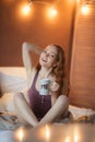 Portrait of young beautiful woman her hands holding cup of coffee morning cold winter time in her white bedroom. Happy Royalty Free Stock Photo