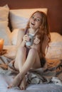 Portrait of young beautiful woman her hands holding cup of coffee morning cold winter time in her white bedroom. Happy Royalty Free Stock Photo