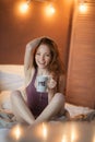 Portrait of young beautiful woman her hands holding cup of coffee morning cold winter time in her white bedroom. Happy Royalty Free Stock Photo