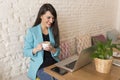 Portrait of a young beautiful woman holding coffee in a restaurant. She is smiling. Modern life of a blogger with computer laptop Royalty Free Stock Photo