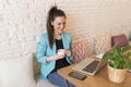 Portrait of a young beautiful woman holding coffee in a restaurant. She is smiling. Modern life of a blogger with computer laptop Royalty Free Stock Photo