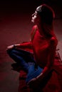 Portrait of a young beautiful woman in with long hair in a Tatar red hat and a red sweater. Fashion photo shoot in low key