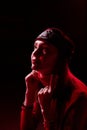 Portrait of a young beautiful woman in with long hair in a Tatar red hat and a red sweater. Fashion photo shoot in low key