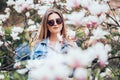 Portrait of a young beautiful woman near magnolia tree with flowers. Royalty Free Stock Photo