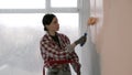 Portrait of young beautiful woman painting walls in beige color with paint roller brush, to redesign room. Home