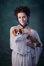 Portrait of young beautiful woman with pale skin and blushing cheeks holding little dog  over dark green Royalty Free Stock Photo