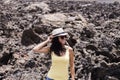 Portrait of a young beautiful woman posing over brown volcanic rocks in Lanzarote, Canary islands. summer
