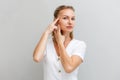 Portrait of a young beautiful woman, pulling the skin on her temples with her fingers. Gray background. The concept of Royalty Free Stock Photo