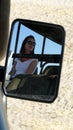 Portrait of young beautiful woman reflected on the car`s mirror of a safari jeep during a morning game in Okavango Delta, Botswana