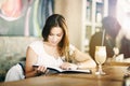 Portrait of a young, beautiful woman sitting alone in a cafe, reading, looking interested and amused.