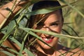 Portrait of young and beautiful woman smiling through the leaves of some reed branches. Concept beauty, fashion, looks, plants,