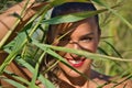 Portrait of young and beautiful woman smiling through the leaves of some reed branches. Concept beauty, fashion, looks, plants,