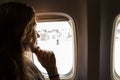 Portrait of young beautiful woman smiling and looking out from jetliner window indoors. Royalty Free Stock Photo