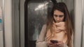 Portrait of young beautiful woman standing in subway. Girl uses smartphone, browse the Internet in metro train Royalty Free Stock Photo