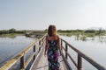 Portrait of young beautiful woman standing on a wood pier in a natural park at sunset. Tourism, love and travel concept Royalty Free Stock Photo