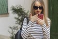 Portrait of a young beautiful woman in striped shirt and sunglasses on street.