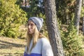 Portrait of young beautiful woman in stylish snow hat and sweater at sunset.Closeup view fashion female in woodland park landscape