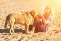 Portrait of young beautiful woman in sunglasses sitting on sand beach hugging golden retriever dog. Girl with dog by sea Royalty Free Stock Photo