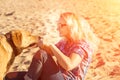 Portrait of young beautiful woman in sunglasses sitting on sand beach hugging golden retriever dog. Girl with dog by sea Royalty Free Stock Photo